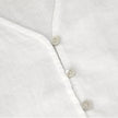 FJØRNA tailored V-neck linen top in light fabric, showcasing a relaxed fit and elegant design on a model.