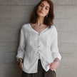 FJØRNA tailored V-neck linen top in light, breathable fabric, featuring a relaxed fit and subtle stitching details.