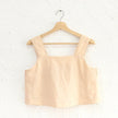 FJØRNA square neck linen cropped tank top displayed on a hanger, showcasing its light, breathable fabric and stylish square neckline.