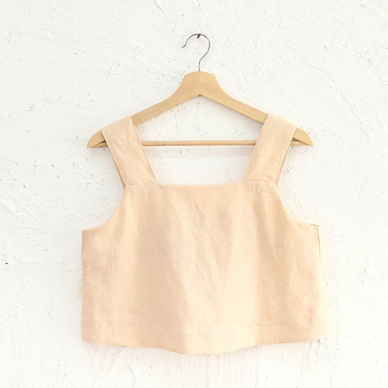 FJØRNA square neck linen cropped tank top displayed on a hanger, showcasing its light, breathable fabric and stylish square neckline.