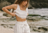 FJØRNA women's linen wide-leg trousers with elastic waist and ruffle detail, showing flowy fabric and relaxed fit.