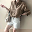 Women’s linen shirt with open collar by FJØRNA, displayed on a hanger, featuring a relaxed fit and lightweight breathable fabric.