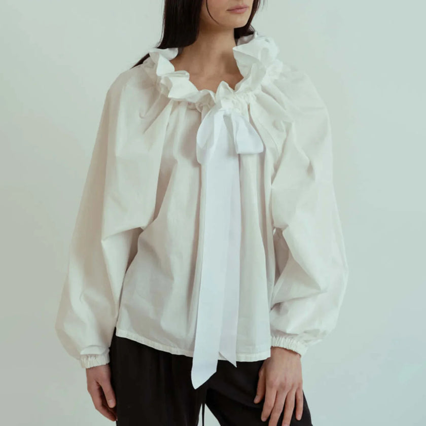 FJØRNA women's cotton blouse with ruffle detail, featuring a feminine and stylish design perfect for casual or dressy occasions.