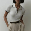FJØRNA women's cotton polo top, stylish short-sleeve blouse with a classic collar and button placket, in soft white fabric.