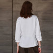 FJØRNA tailored V-neck linen top in neutral color, featuring a relaxed fit and lightweight fabric for warm weather wear.