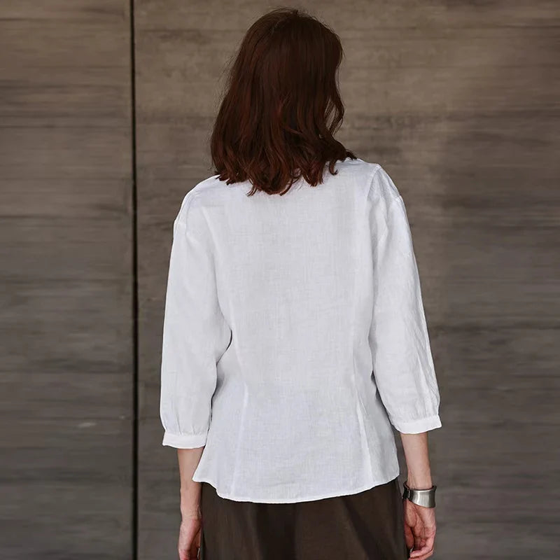 FJØRNA tailored V-neck linen top in neutral color, featuring a relaxed fit and lightweight fabric for warm weather wear.