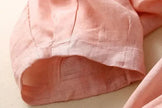 FJØRNA women's linen tapered trousers featuring a relaxed fit and natural beige color, displayed on a model.