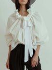 FJØRNA women's cotton blouse with ruffle detail, featuring a soft fabric and feminine design, perfect for casual or dressy occasions.