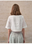 FJØRNA women's linen crop top with short sleeves, lightweight and breathable, shown in a natural pose.