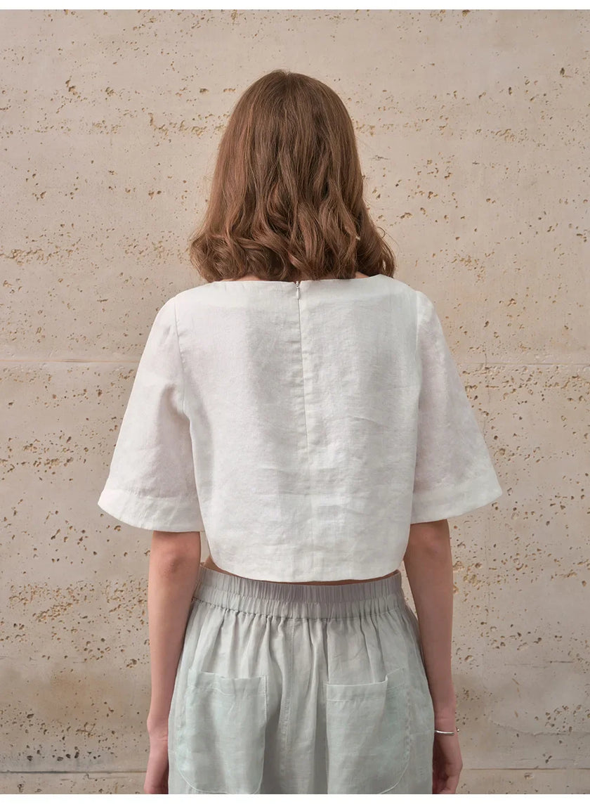FJØRNA women's linen crop top with short sleeves, lightweight and breathable, shown in a natural pose.