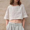 FJØRNA women's linen crop top with short sleeves, lightweight and breathable, shown in a natural fit on a model.