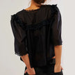 FJØRNA women's cotton blouse with ruffle detail, showcasing a stylish and lightweight top with feminine design and soft fabric.