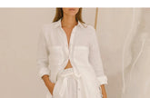 FJØRNA linen wide-leg women's trousers with elastic waist and ruffle detail, shown in natural fabric with relaxed fit.