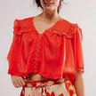 FJØRNA women's cotton blouse with ruffle details, featuring a stylish and comfortable top with feminine design.