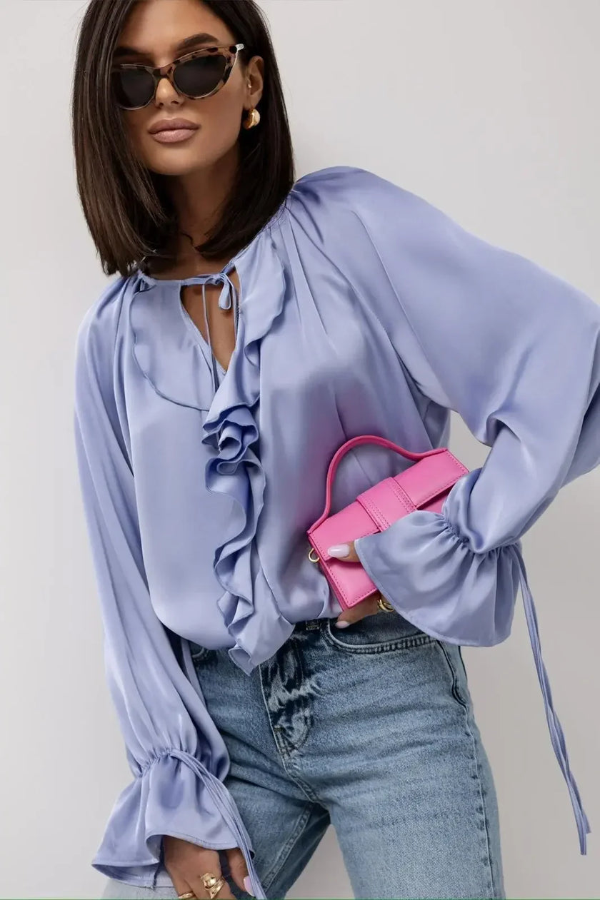 FJØRNA women's satin blouse with ruffle detail, stylish top featuring a smooth, shiny fabric and elegant design.