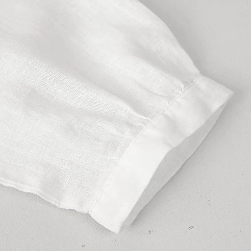 FJØRNA tailored V-neck linen top in neutral color, featuring a fitted design and lightweight fabric for a stylish, comfortable look.
