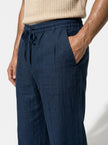 Men's linen trousers by FJØRNA with relaxed fit, breathable fabric, ideal for summer, shown in a close-up shot.