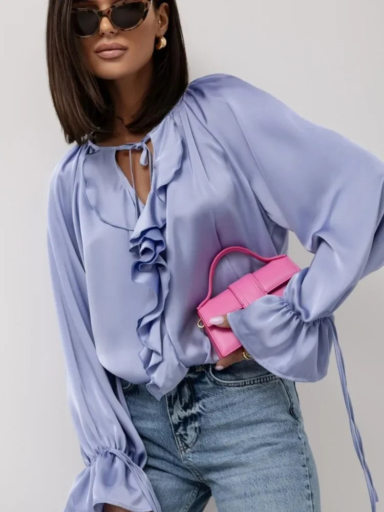 FJØRNA satin women’s blouse with ruffle detail, elegant long-sleeve top featuring a smooth, shiny fabric and feminine design.