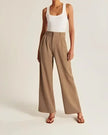 FJØRNA women's wide-leg high-waist trousers, stylish pants with a relaxed fit and tailored design, shown in neutral fabric.