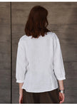 FJØRNA tailored V-neck linen top in neutral color, close-up of soft fabric and stylish fit for casual or summer wear.