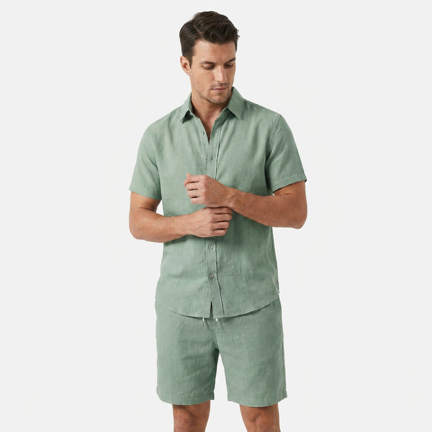 Men's sage green linen short sleeve shirt and shorts two-piece set by FJØRNA, displayed with sleeves adjusted for pose.