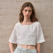 FJØRNA women’s linen crop top with short sleeves, lightweight and breathable, shown on a model with a casual summer outfit.