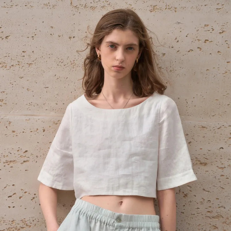 FJØRNA women’s linen crop top with short sleeves, lightweight and breathable, shown on a model with a casual summer outfit.
