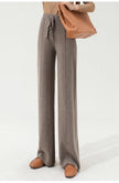 FJØRNA women's merino wool wide-leg high-waist trousers hanging on a wooden hanger, showcasing the stylish and comfortable design.