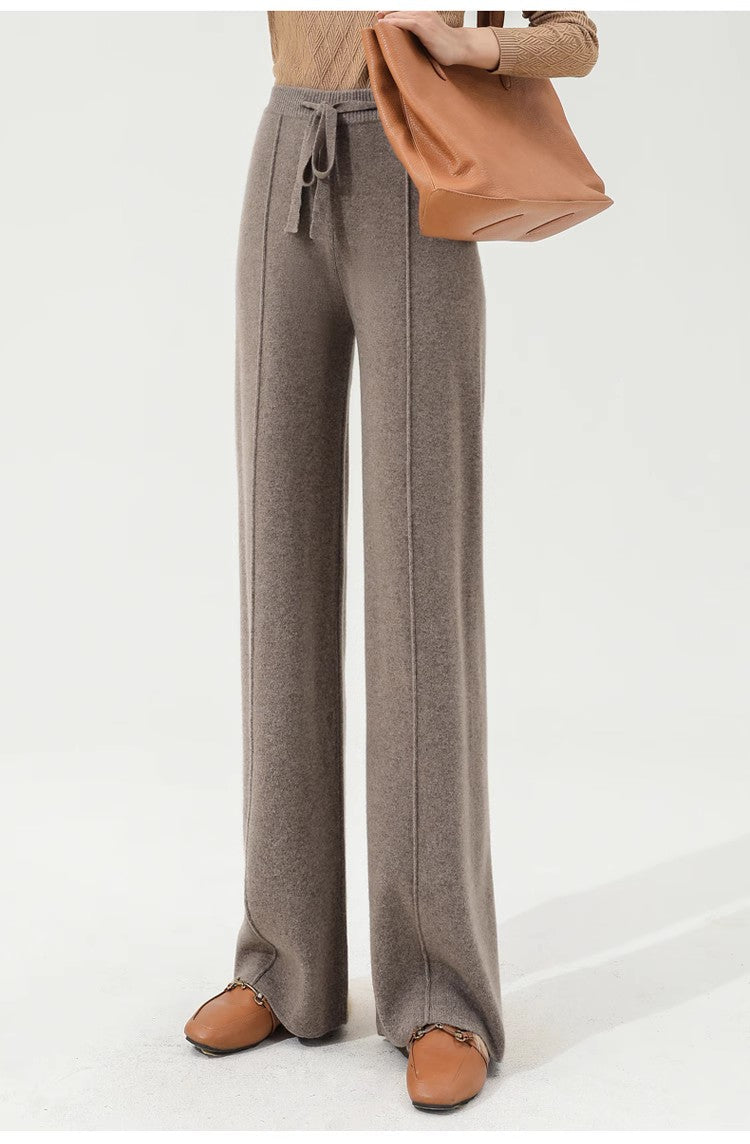FJØRNA women's merino wool wide-leg high-waist trousers hanging on a wooden hanger, showcasing the stylish and comfortable design.