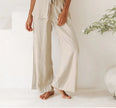 FJØRNA linen wide-leg women's trousers with elastic waist and ruffle detail, stylish and comfortable for casual wear.