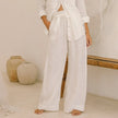 FJØRNA women's linen wide-leg trousers with elastic waist and ruffle details, styled on a model showcasing relaxed fit and lightweight fabric.