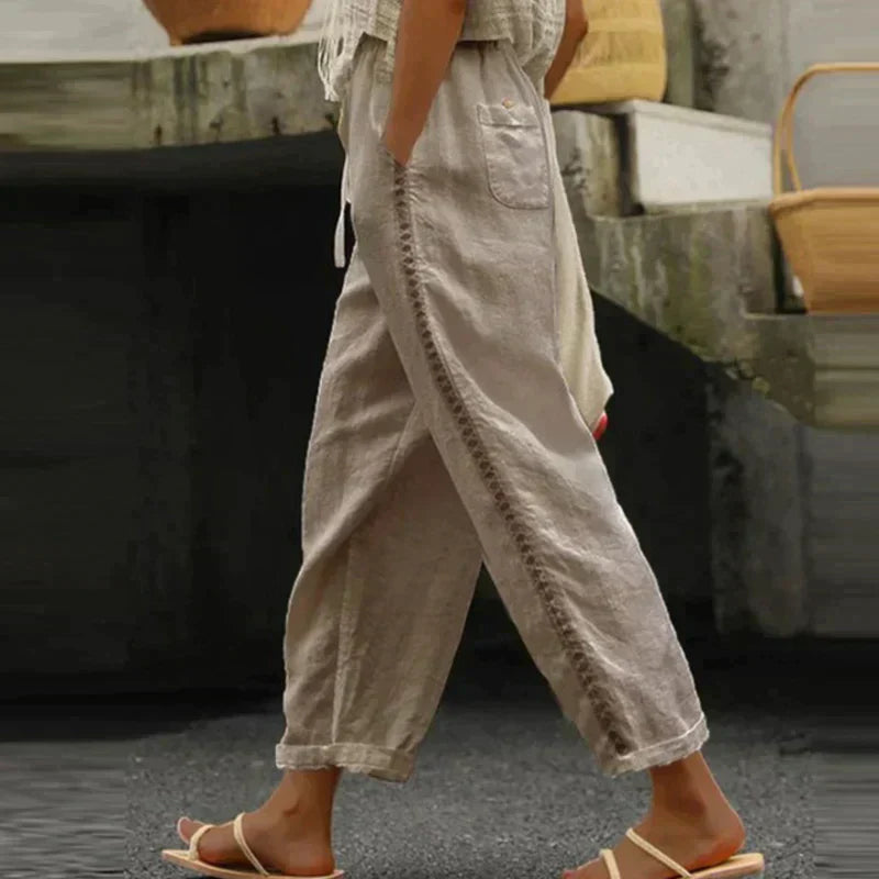 FJØRNA women's linen summer trousers with high waist and tapered fit, showcasing breathable, lightweight fabric in a natural pose.