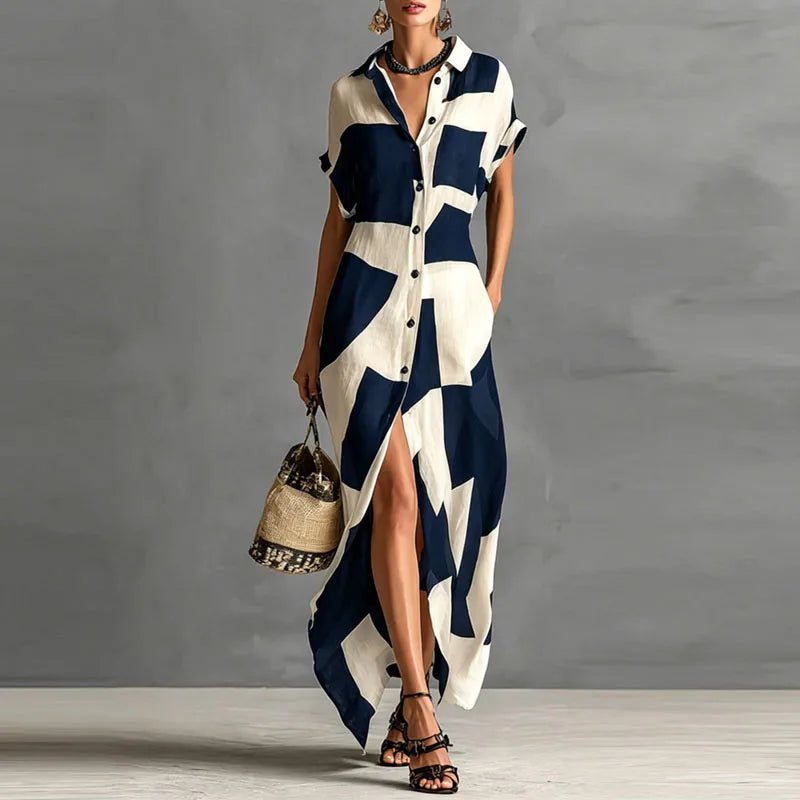 FJØRNA Victoria printed button-down maxi dress in white with floral patterns, flowing fabric, and long sleeves.