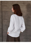 FJØRNA tailored V-neck linen top displayed on a hanger, showcasing its lightweight, breathable fabric and classic fit.