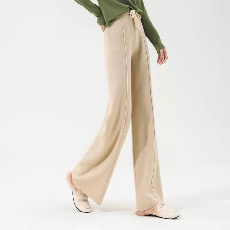 FJØRNA women's merino wool wide-leg high-waist trousers hanging on a rack, showcasing soft, comfortable fabric and stylish fit.