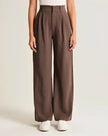 Wide-leg high-waist women's trousers from FJØRNA, featuring a relaxed fit and classic style, shown in a neutral fabric.