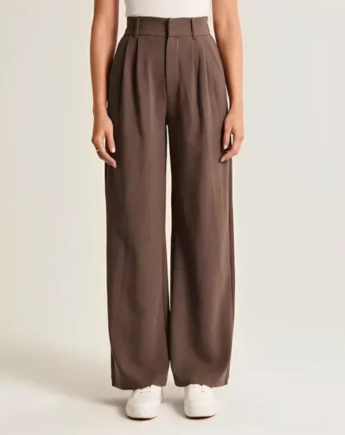 Wide-leg high-waist women's trousers from FJØRNA, featuring a relaxed fit and classic style, shown in a neutral fabric.
