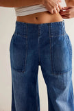 FJØRNA women's wide-leg denim jeans with a relaxed fit, shown hanging on a wooden hanger against a neutral background.