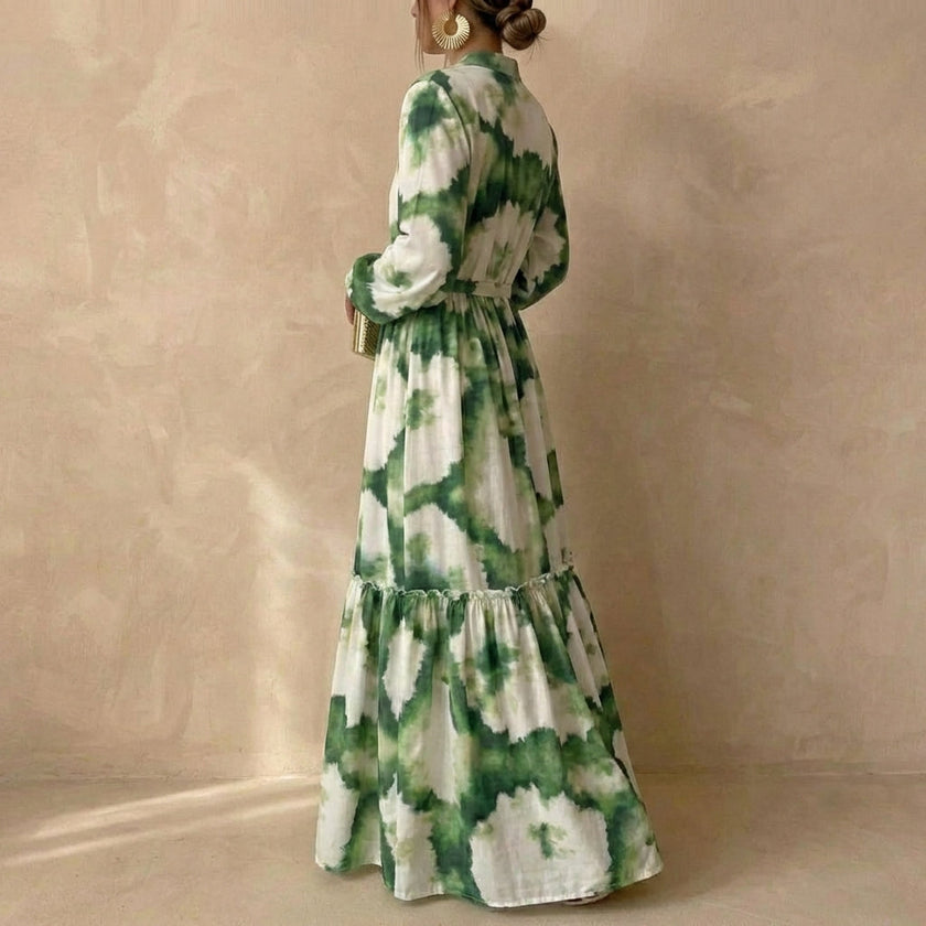 FJØRNA A-line maxi dress with V-neck and puff sleeves shown from side view, flowing fabric and elegant silhouette.