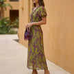 FJØRNA A-line wrap front maxi dress with V-neck, shown from the side, featuring flowing fabric and elegant silhouette.