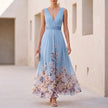 Sky blue floral A-line maxi dress with sleeveless V-neck by FJØRNA, shown on a hanger with a floral print and flowing fabric.