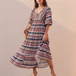 FJØRNA elegant flowing V-neck midi dress with puff sleeves and tiered skirt featuring striped pattern.
