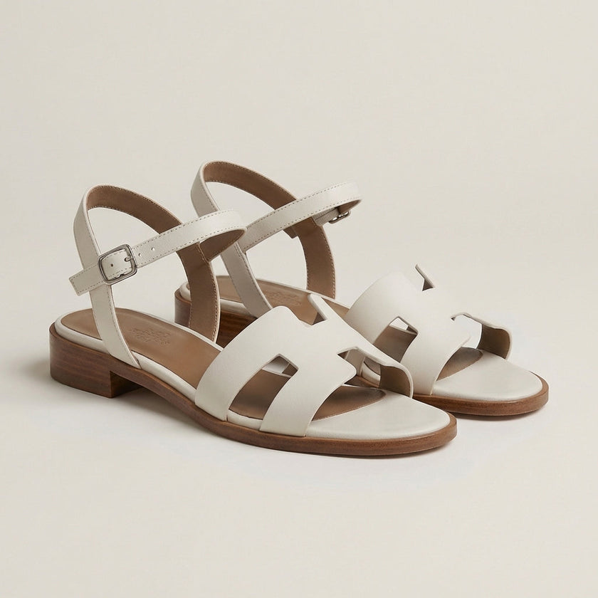 FJØRNA ankle-length flat sandals with ankle strap and buckle, stylish open-toe footwear in a studio setting