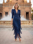 FJØRNA elegant women's V-neck fringe dress, flowing fabric, stylish design, worn by woman with long hair and neutral background.