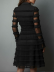 Black FJØRNA mini dress with sheer layered panels and lace details, showcasing a stylish, fitted silhouette.