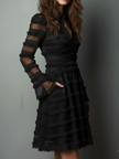 Black FJØRNA mini dress with sheer layered panels and lace details, featuring a stylish design and front pocket.