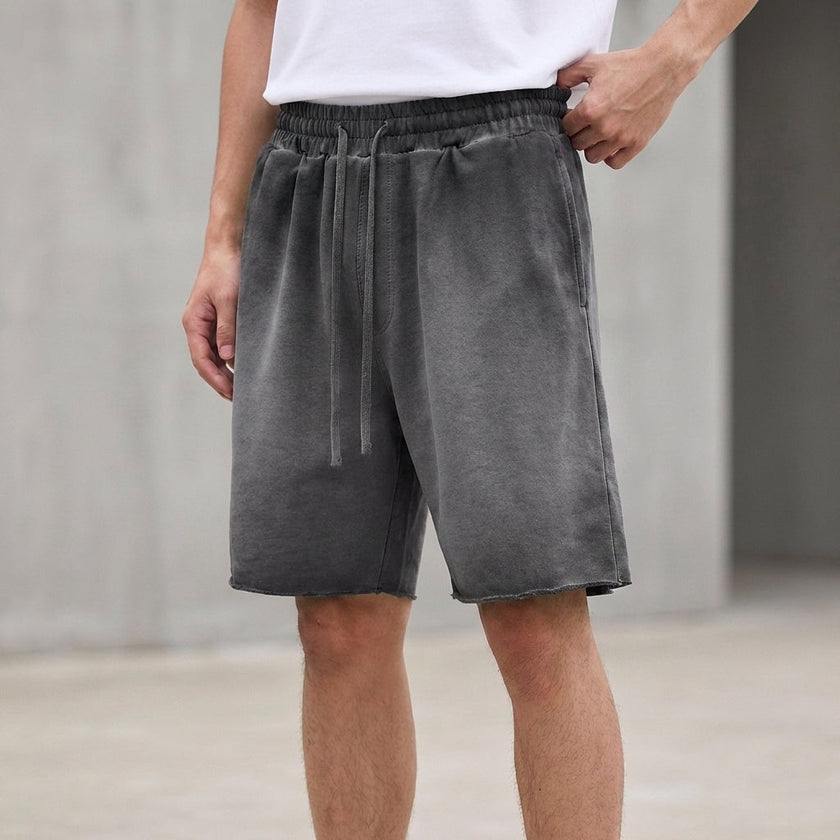 Men's casual knit shorts by FJØRNA with distressed finish, raw hem, and relaxed fit, shown in washed ash color.