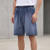 Men's washed blue FJØRNA casual knit shorts with distressed finish and raw hem, relaxed fit and comfortable style.