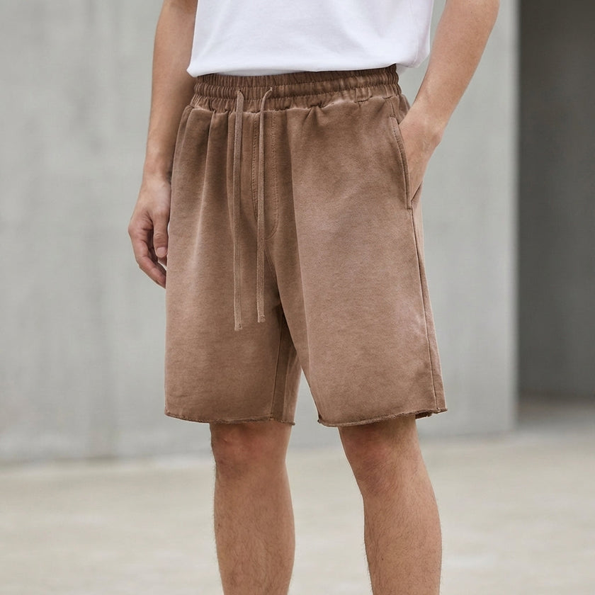 Men's relaxed knit shorts by FJØRNA with distressed finish and raw hem, shown in washed coffee color.