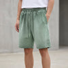 Men's washed green knit shorts by FJØRNA with a relaxed fit, distressed finish, and raw hem, perfect for casual wear.